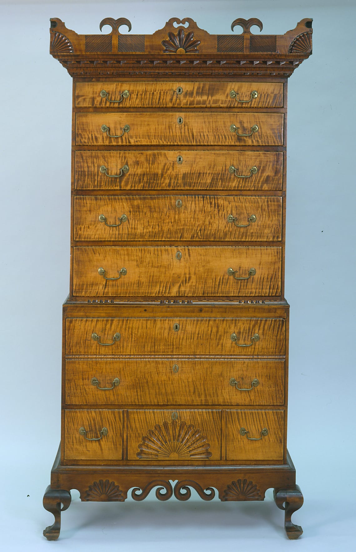 a tall chest of drawers with highly figured wood and a decorative top