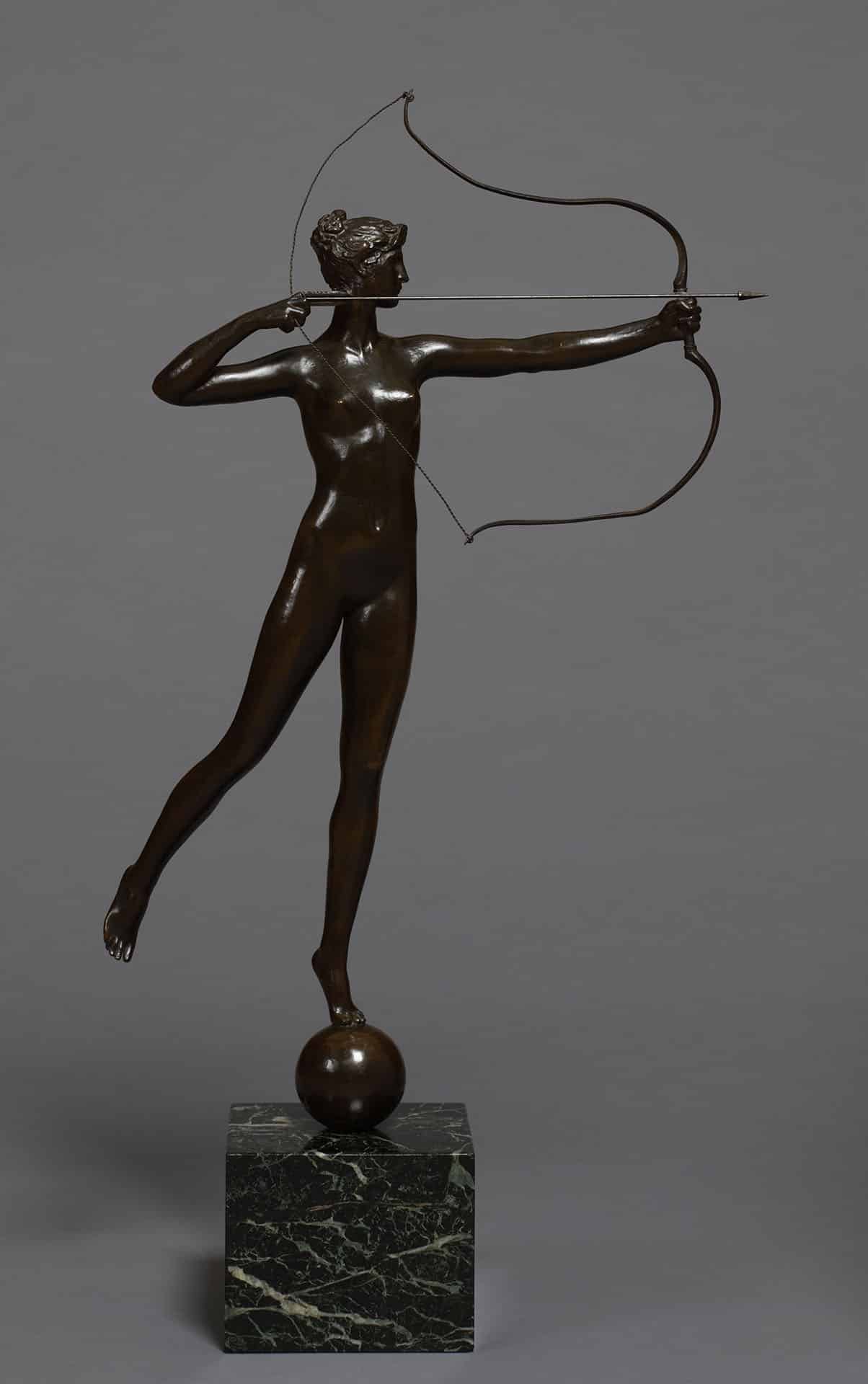 a bronze statue of a nude woman pulling an arrow back holding a bow