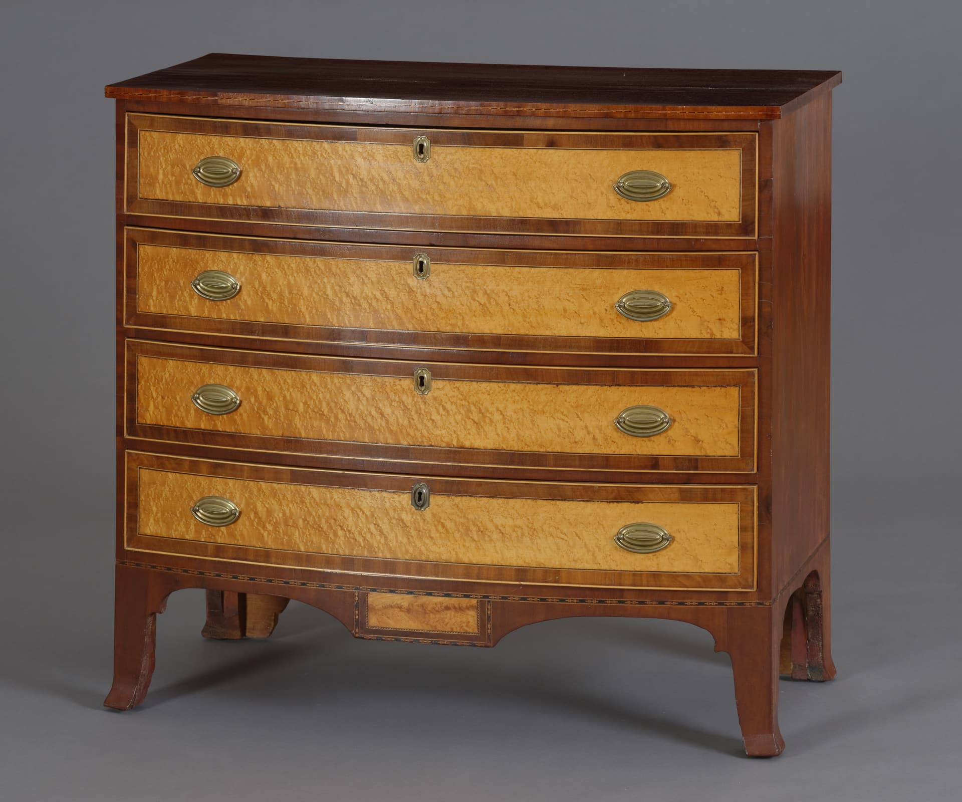 a chest of 4 drawers with lighter wood on the face of the drawers and darker wood for the case
