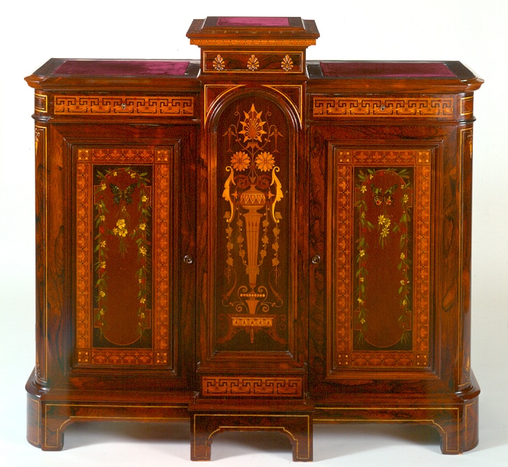 a wood cabinet with ornate decoration of swags and garlands