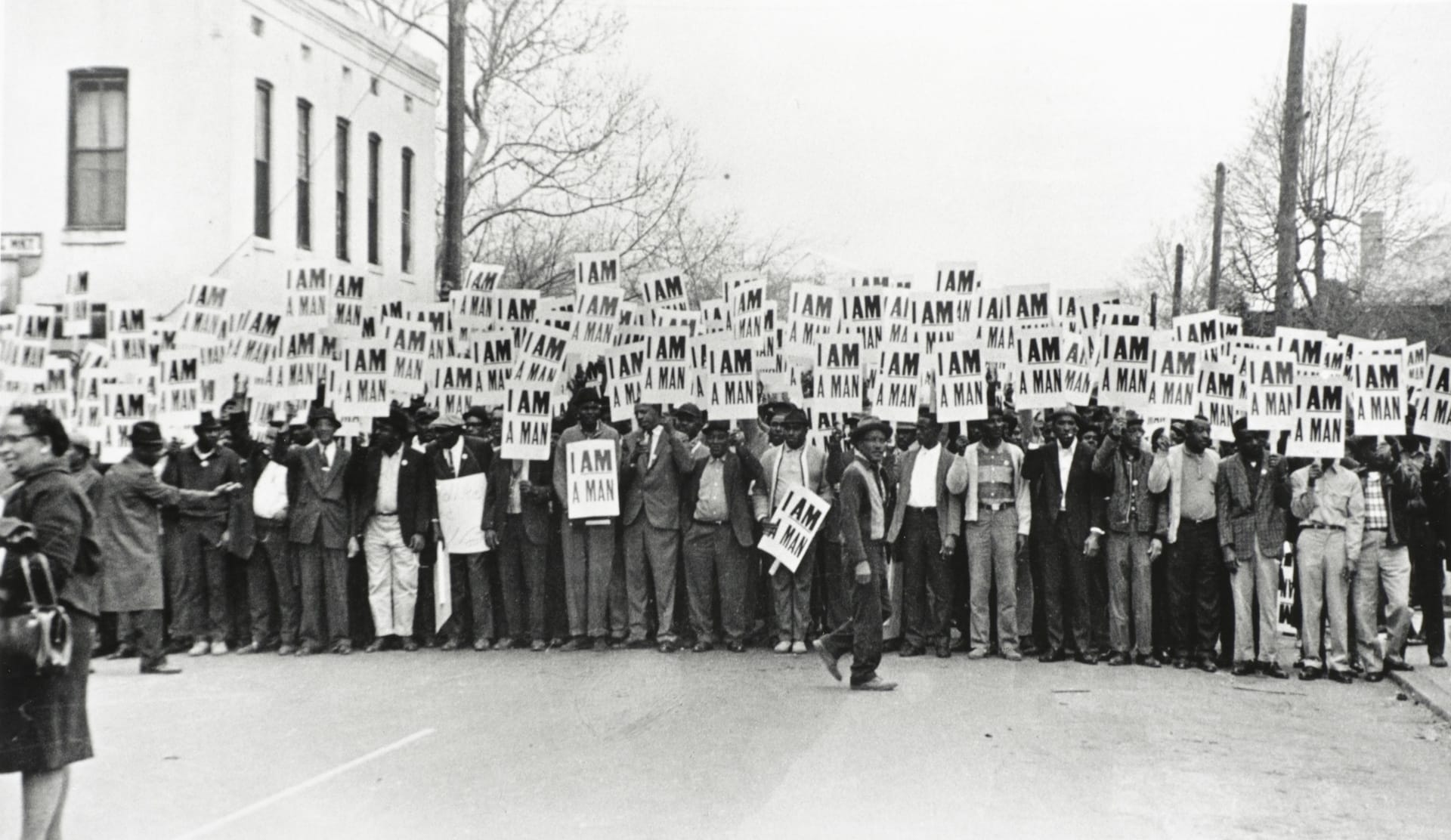 a black-and-white photograph of a crowd of Black protesters holding signs saying 