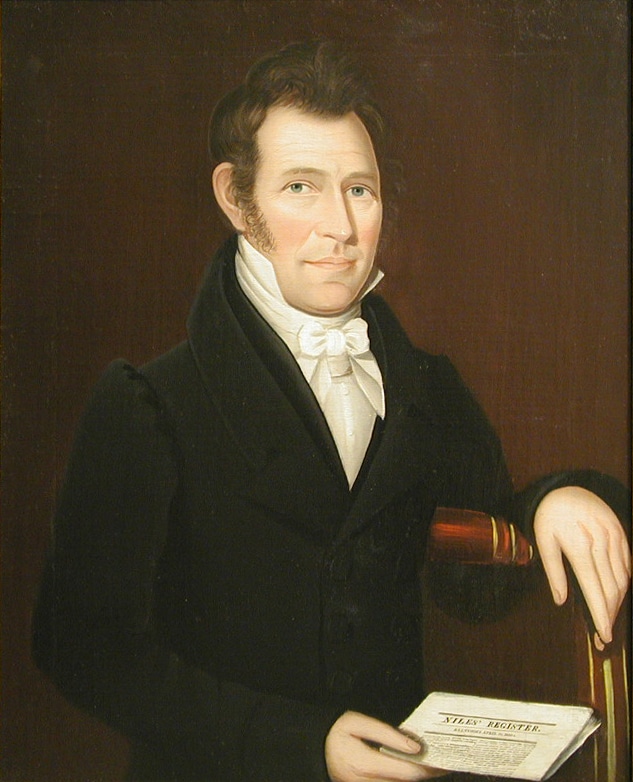 a portrait of a man wearing a black suit jacket and holding a piece of paper