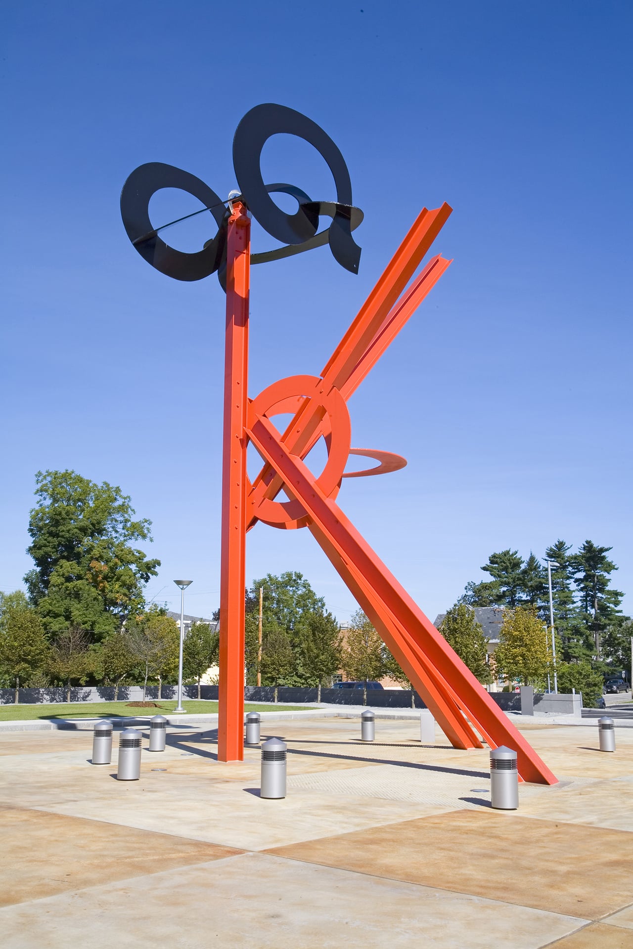 a monumental red sculpture in the shape of a K with a red circle at the center and 3 black disks at the top
