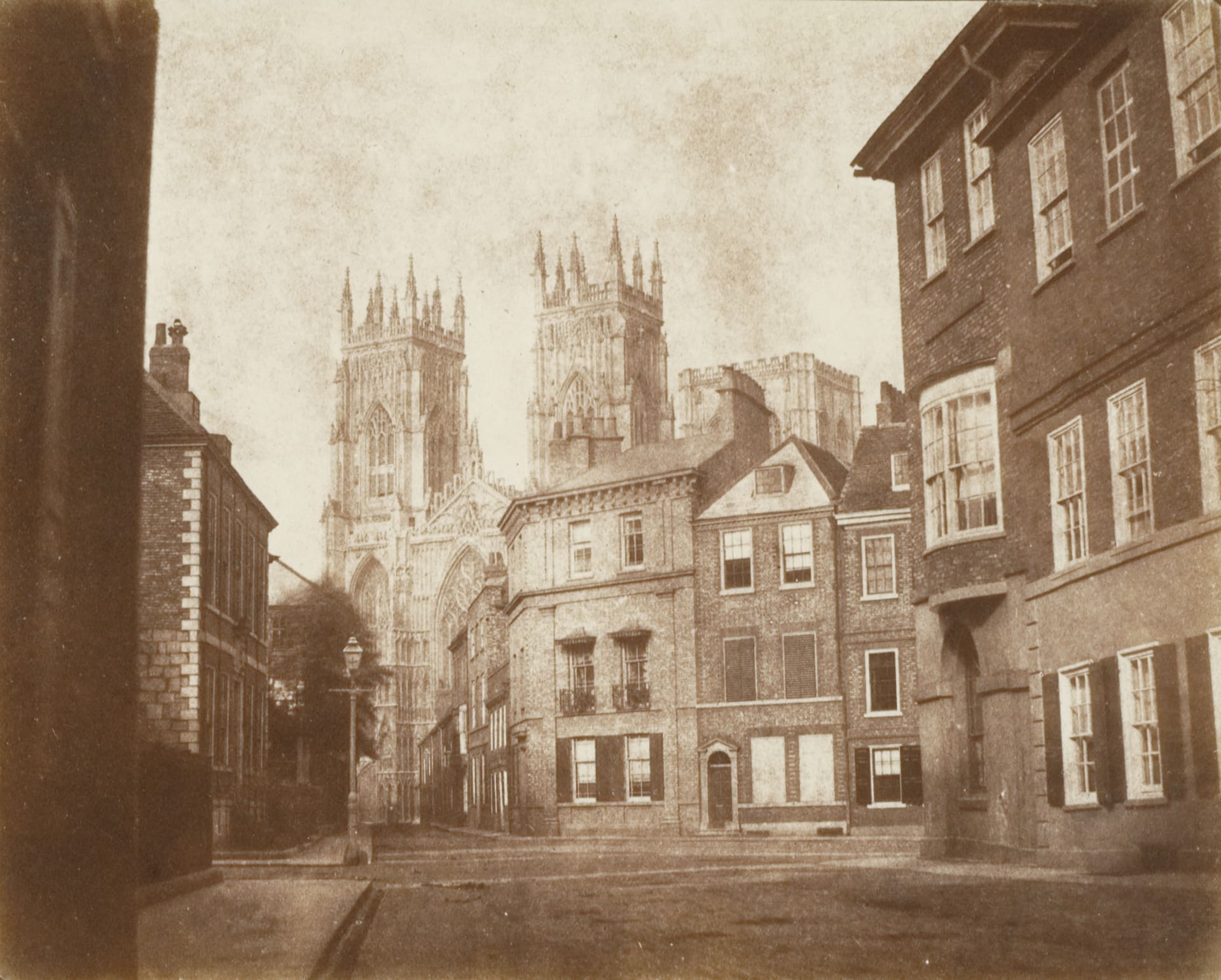 a sepia-toned photograph of a city view with a two-towered church