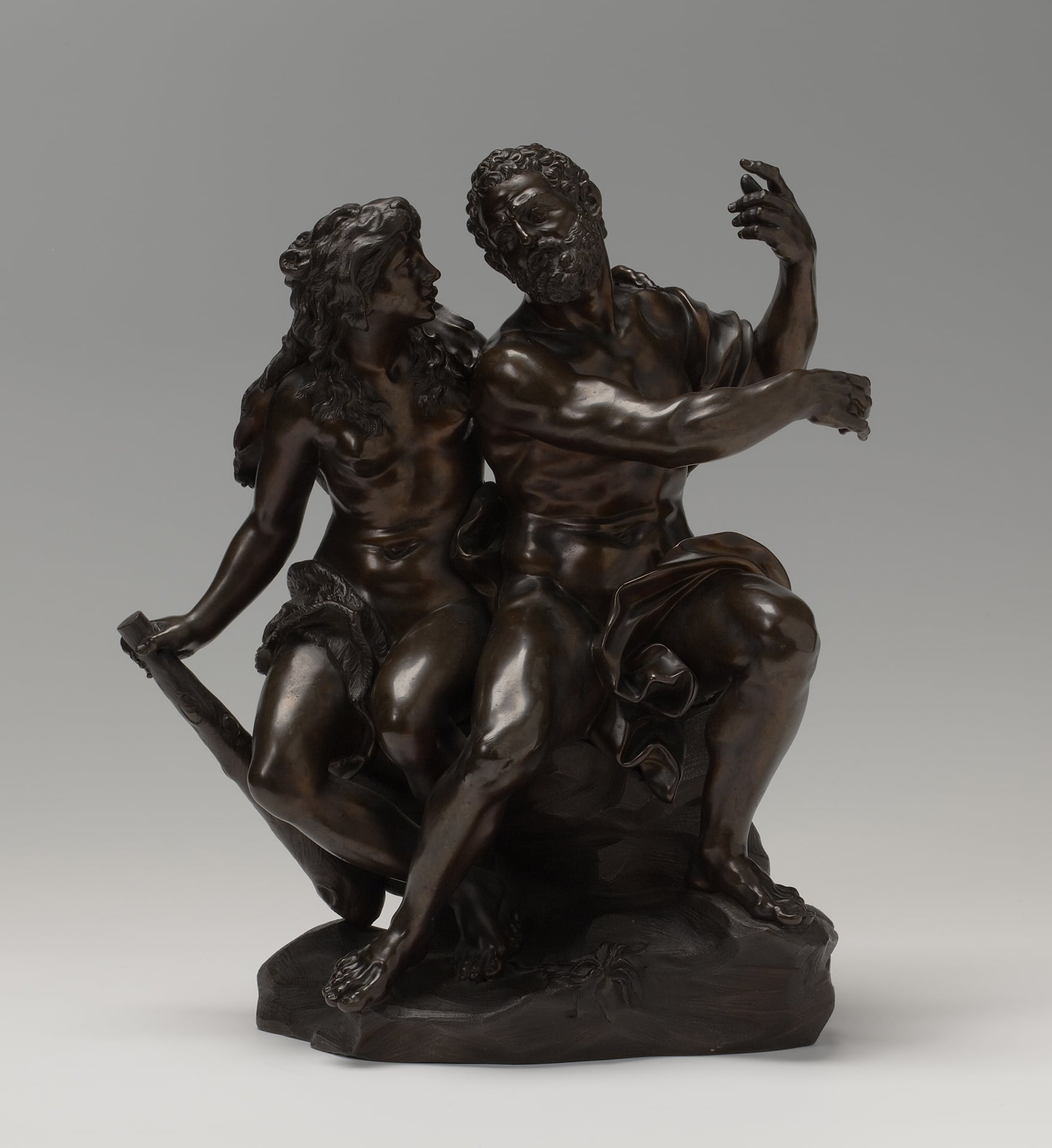 a bronze sculpture of a seated man and woman conversing with each other