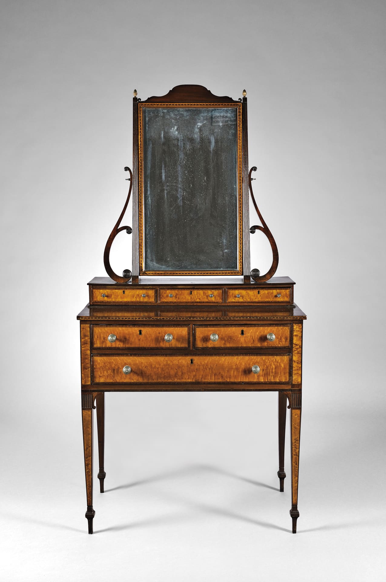 a dressing table with 3 sets of drawers, thin legs and a mirror on top
