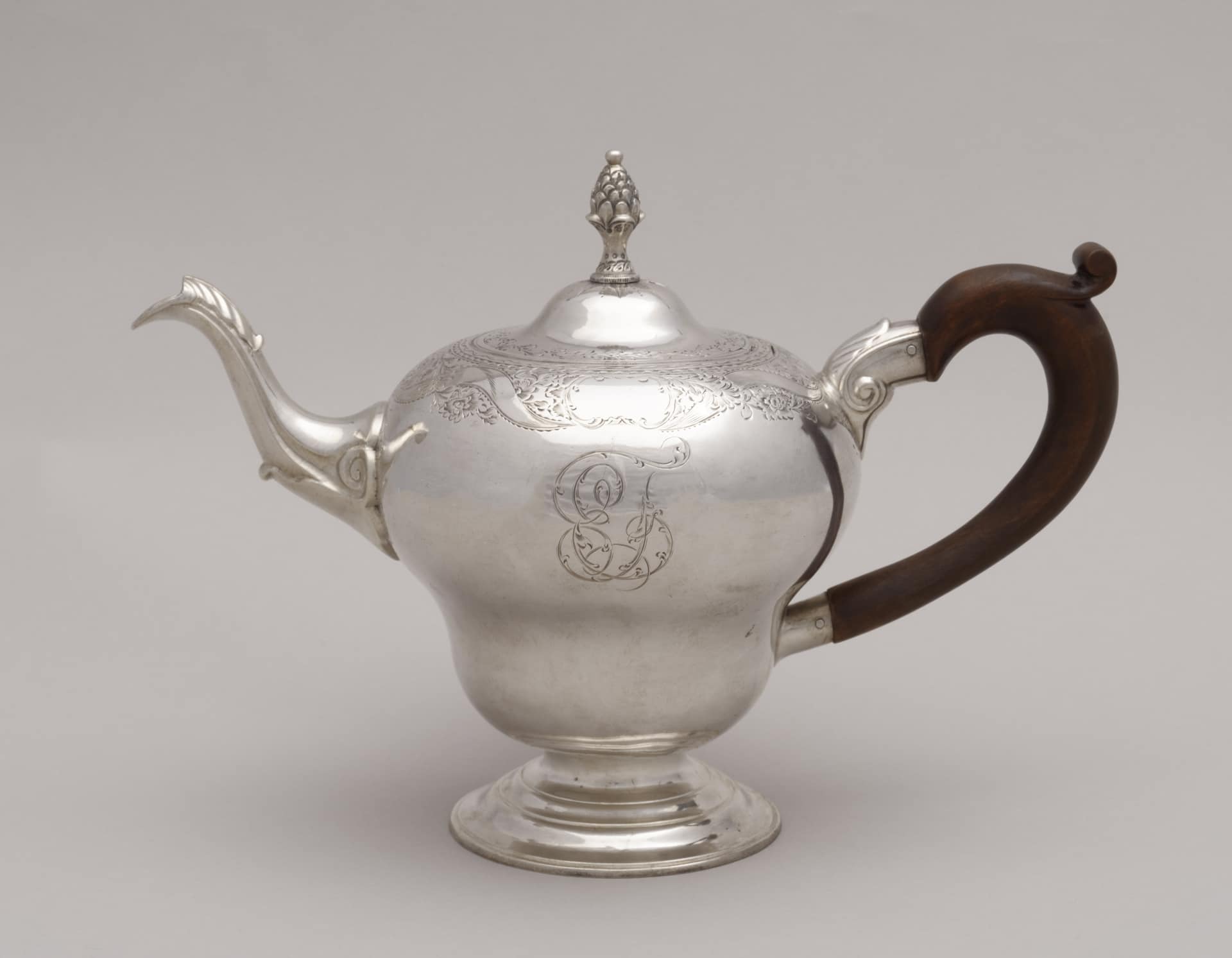a silver teapot with engraved decoration