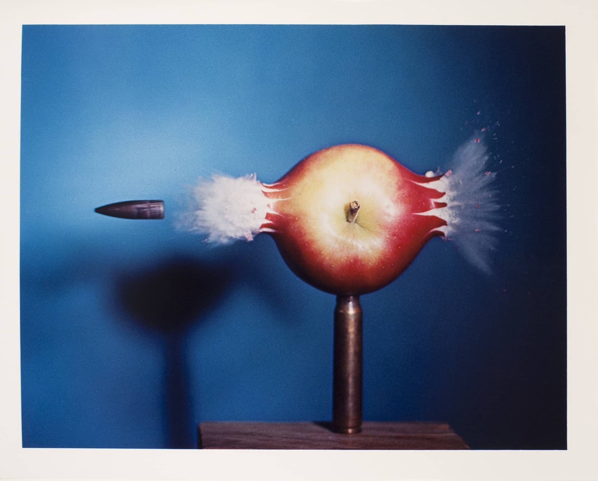 a photograph of a bullet moving through an apple