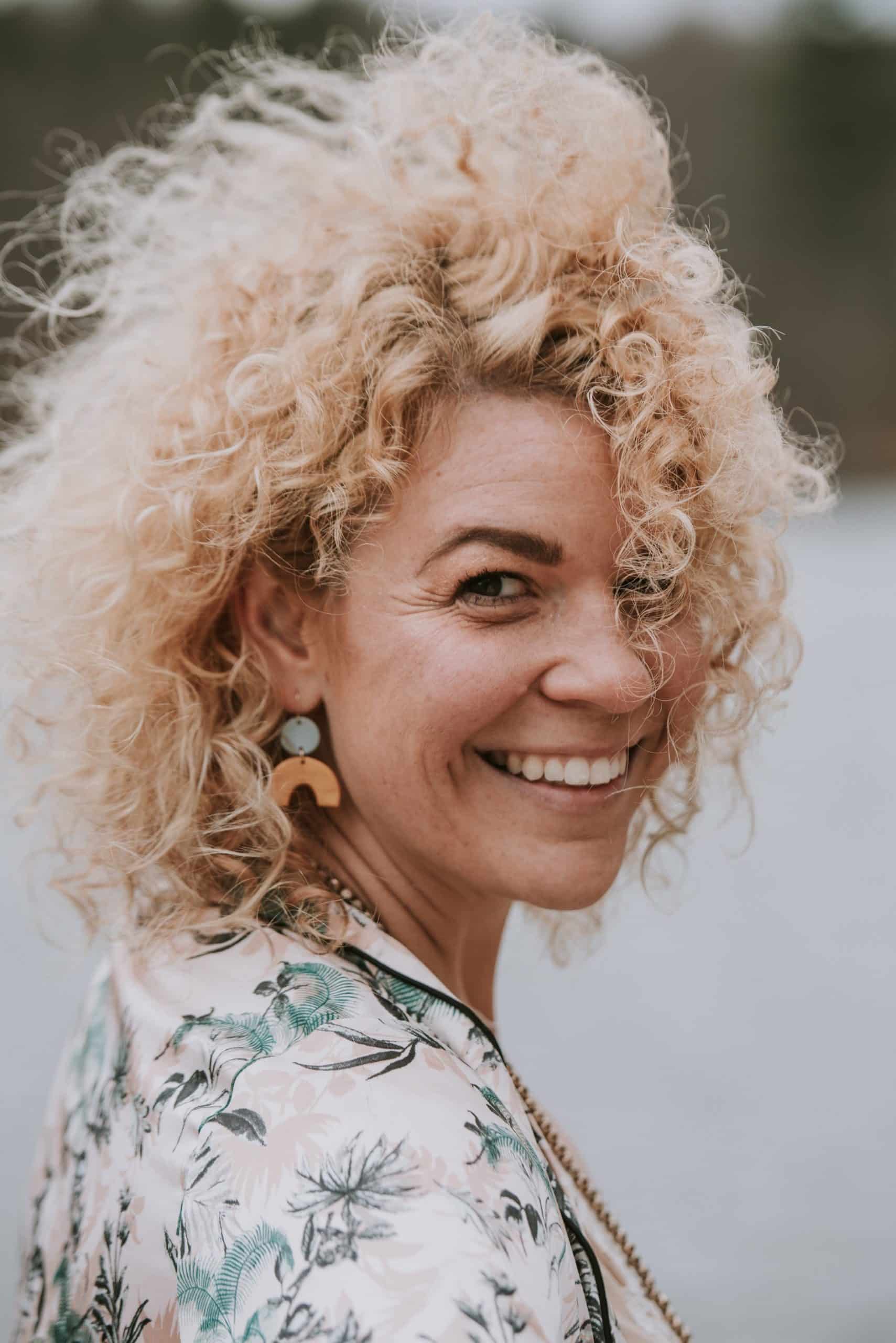 Woman with blond curly hair turning and smiling to the camera