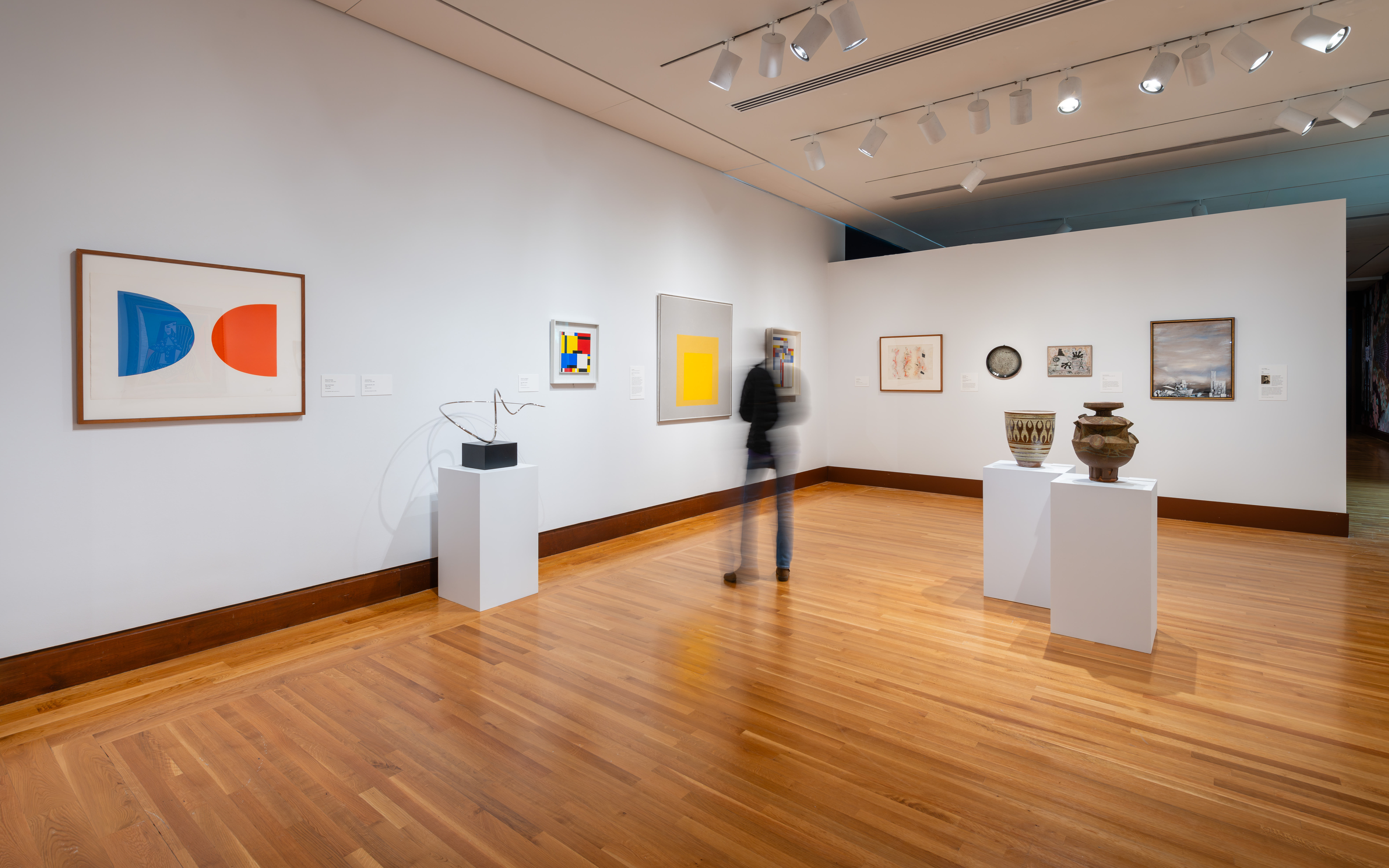 A female museum guest views a work by Josef Albers in an art gallery with paintings and sculptures on view