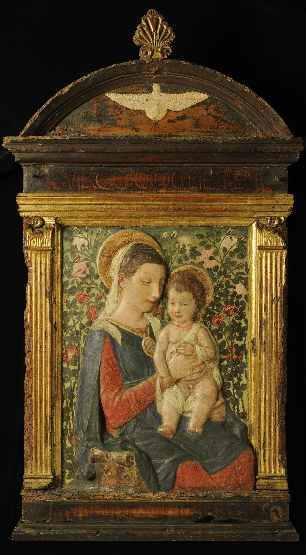 a painted wood relief of the madonna holding the christ child on her lap